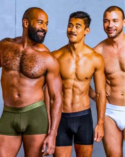 Three men standing side by side wearing underwear against a plain background
