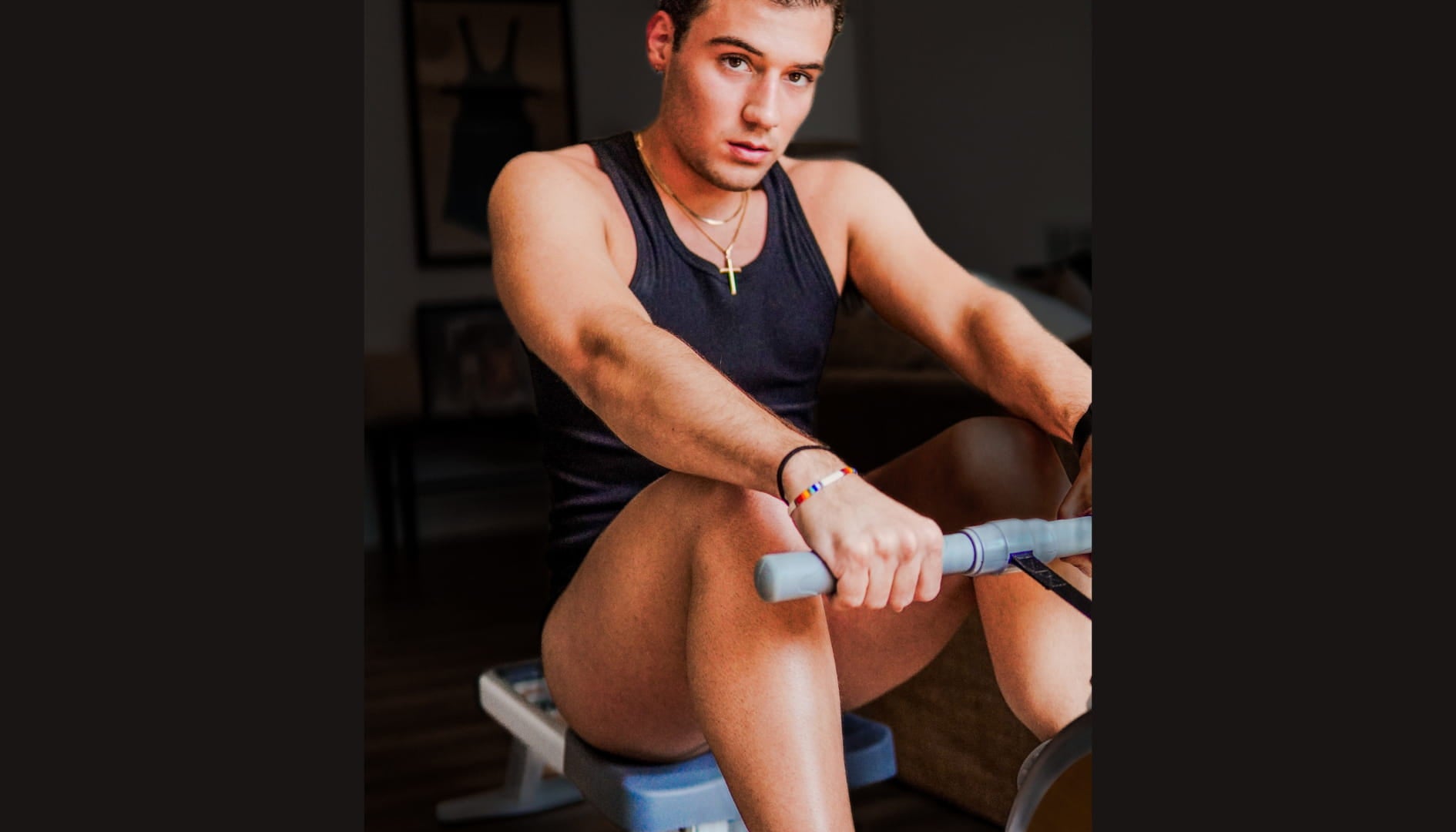 Man exercising on a rowing machine in a home setting wearing ALPHX Modern Fit Black Trunks