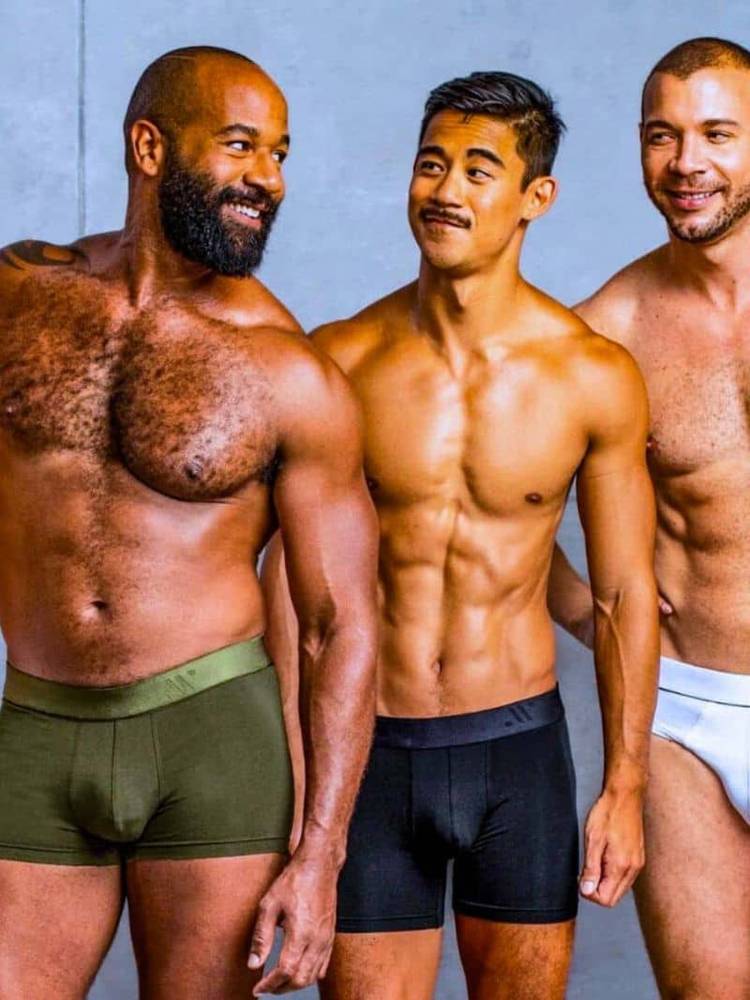 Three men wearing underwear against a plain background