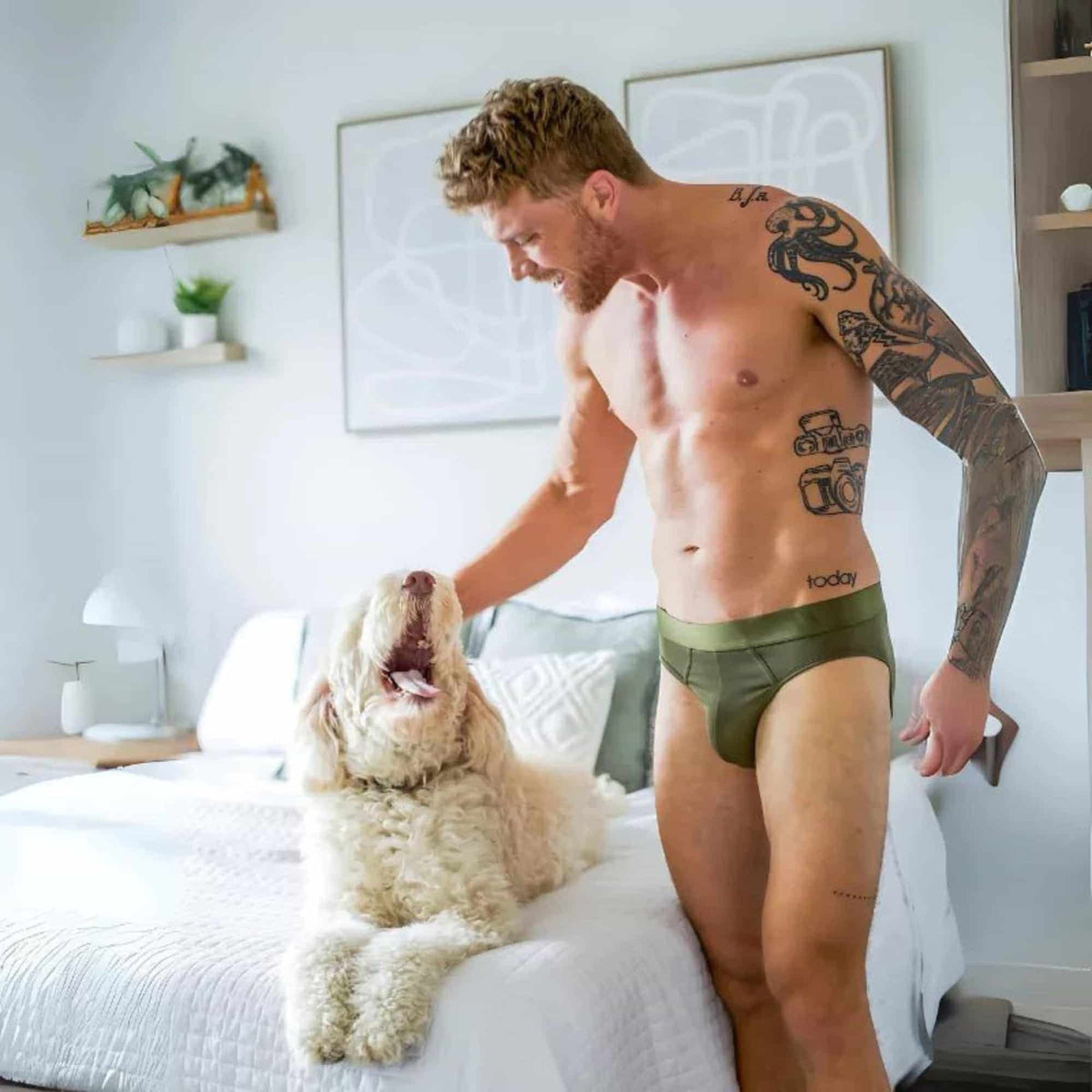 Man wearing ALPHX modern briefs in winter moss petting dog in bedroom.