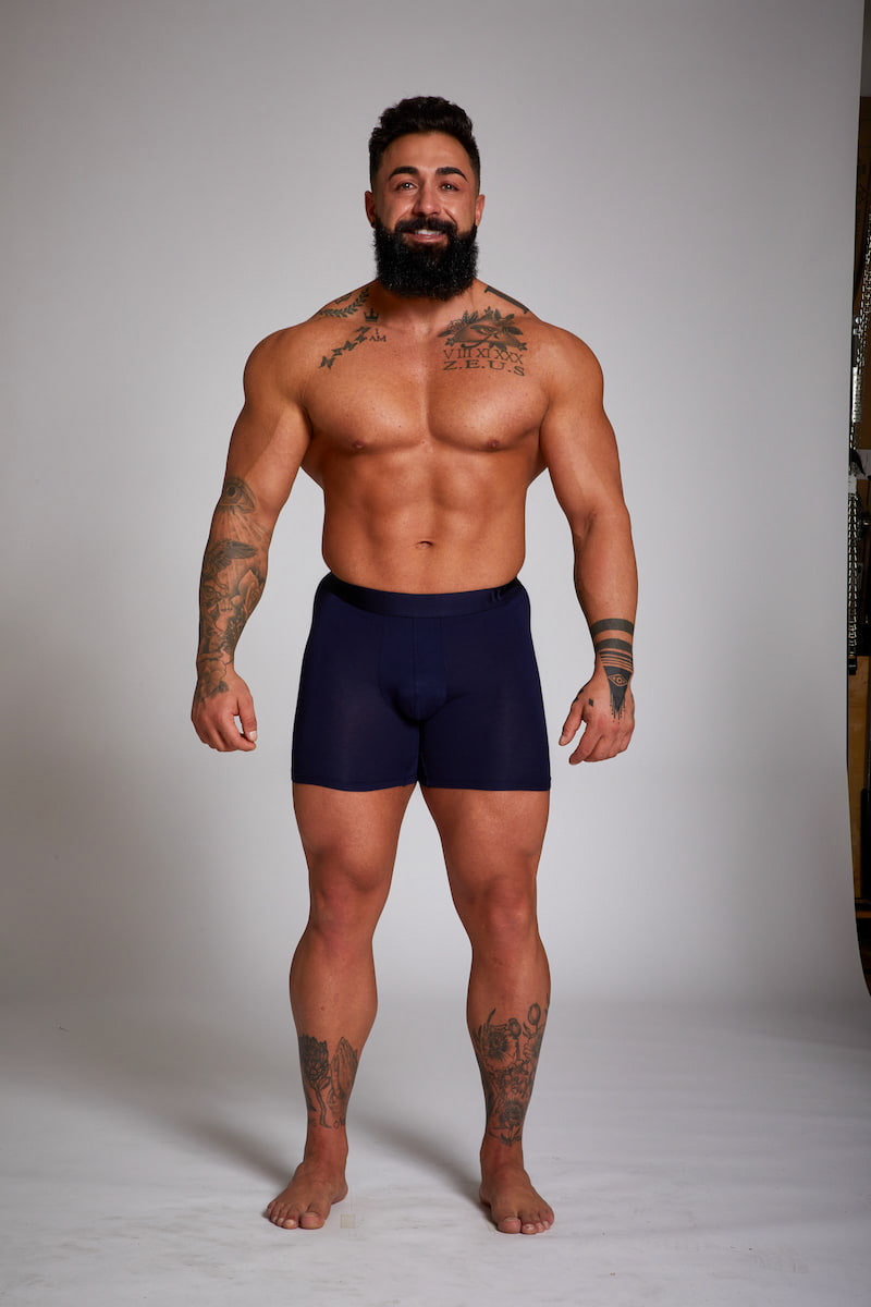 Man wearing navy blue boxer briefs against a plain background