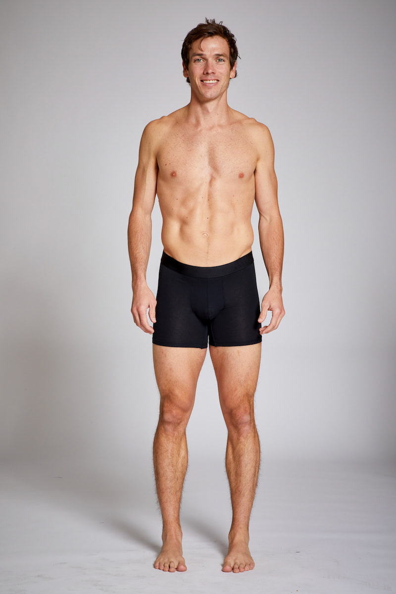 Man wearing black boxer briefs against a plain background