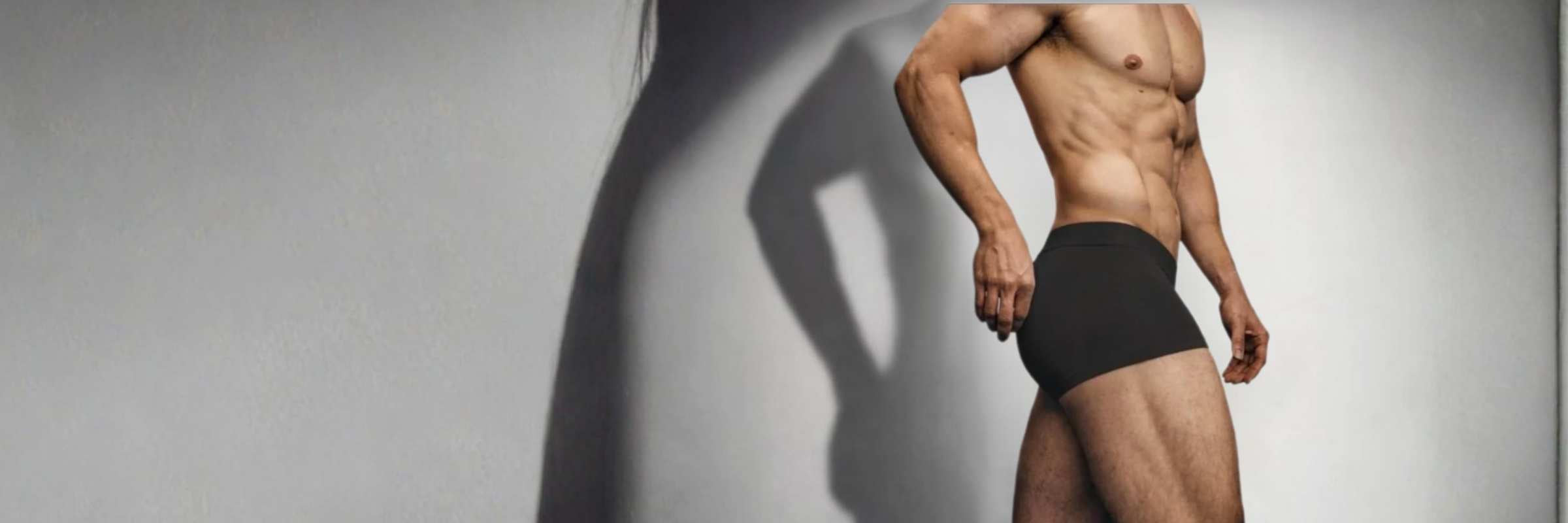 Man wearing black underwear against a plain background
