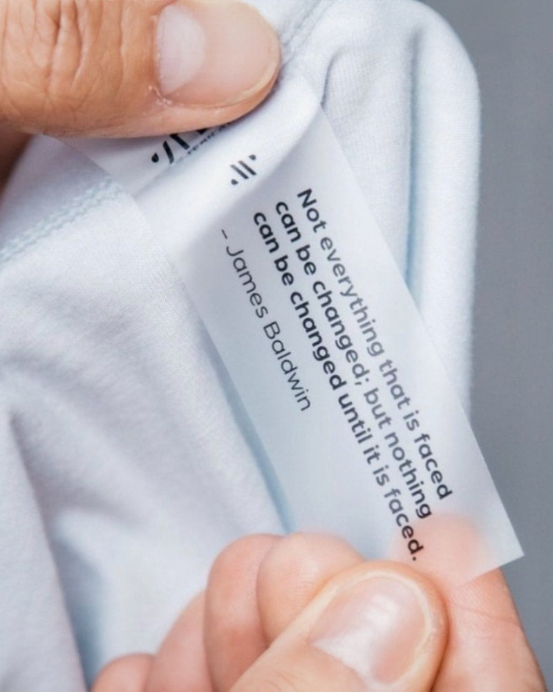 Close-up of ALPHX tear-away tag featuring motivational quote by James Baldwin—part of the brand’s tagless, comfort-first underwear design.