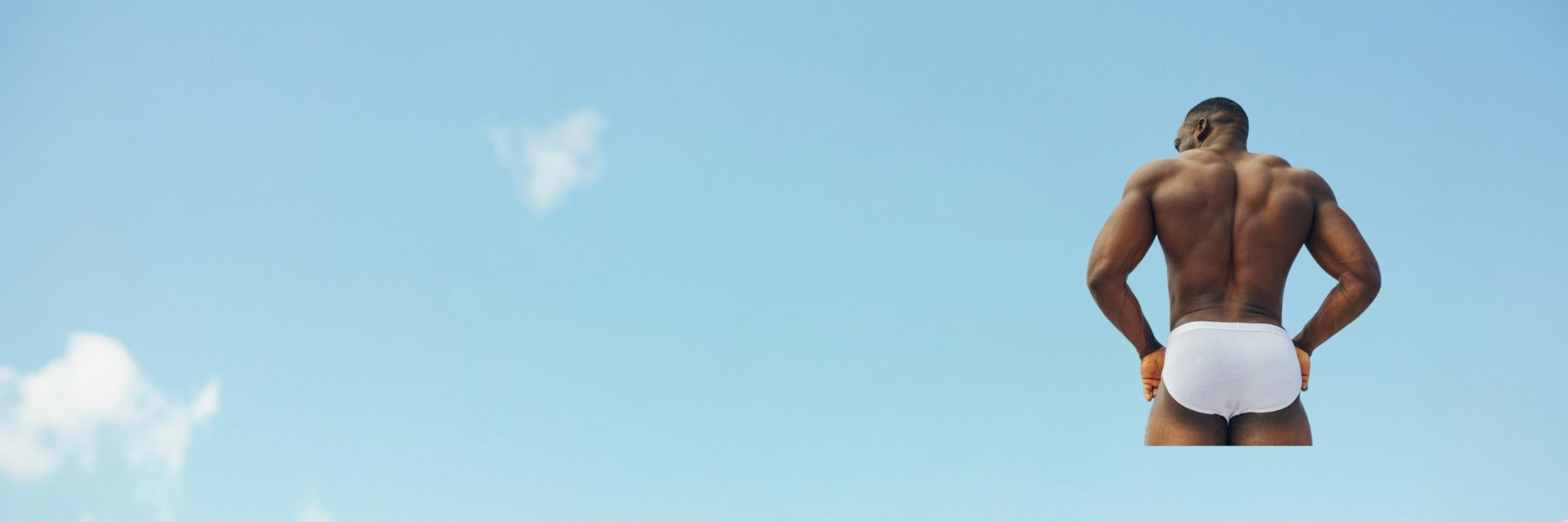 Man in white underwear standing on a diving board with a clear blue sky in the background