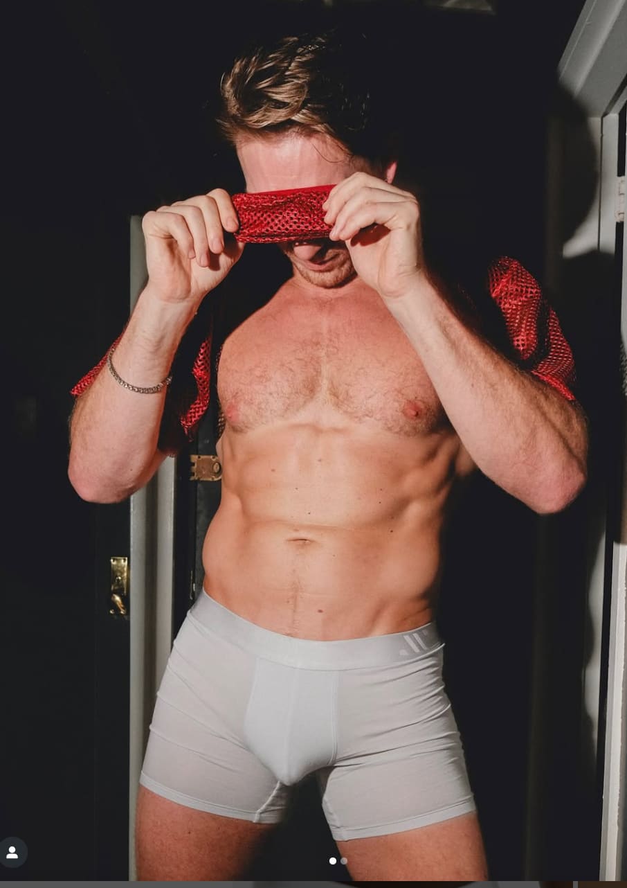 Man wearing ALPHX boxer briefs in Glacier Blue with red mesh tank pulled up