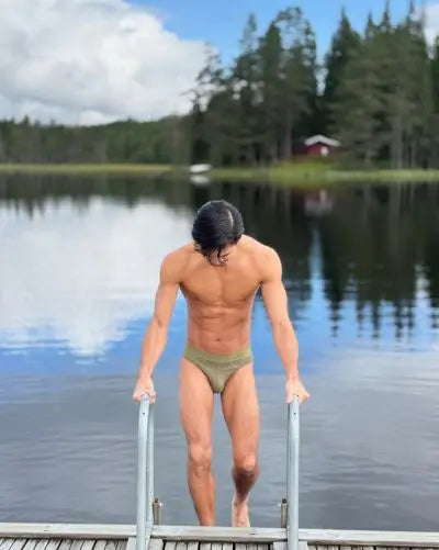 Man standing on a dock by a lake with trees in the background