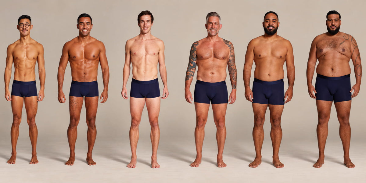 Six men standing side by side wearing ALPHX Modern Fit Trunks, one for each size from XS to 2XL, showing how each waist size fits different body types